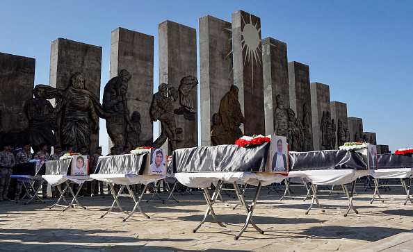 TOPSHOT - People attend a funeral ceremony for the remains of 41 victims from the Yazidi minority, who were executed by Islamic State (IS) group militants in 2014, in front of a memorial monument in Sinjar in northwestern Iraq's Nineveh province on January 24, 2024. The victims of the August 2014 massacre, carried out in the Sinjar region by IS group militants, have been recently identified through DNA tests.